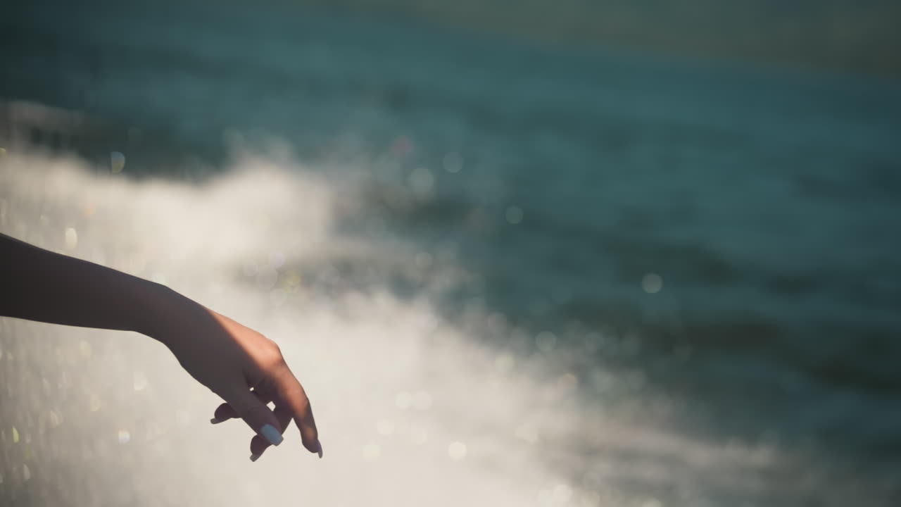 Elegant woman hand against foam trail at yacht cruise closeup. Lady enjoys freshness on motorboat sailing sea on summer vacation. Marine scene