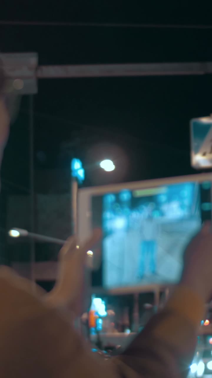 Person using tablet at pedestrian crossing at night