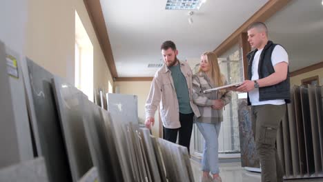 a Young Couple Considers what Color to Choose for their Home at a Ceramic Tile Shop a Young Couple is Talking to a Sales Clerk about Interior Decoration in a Ceramic Tile Shop Choice Concept