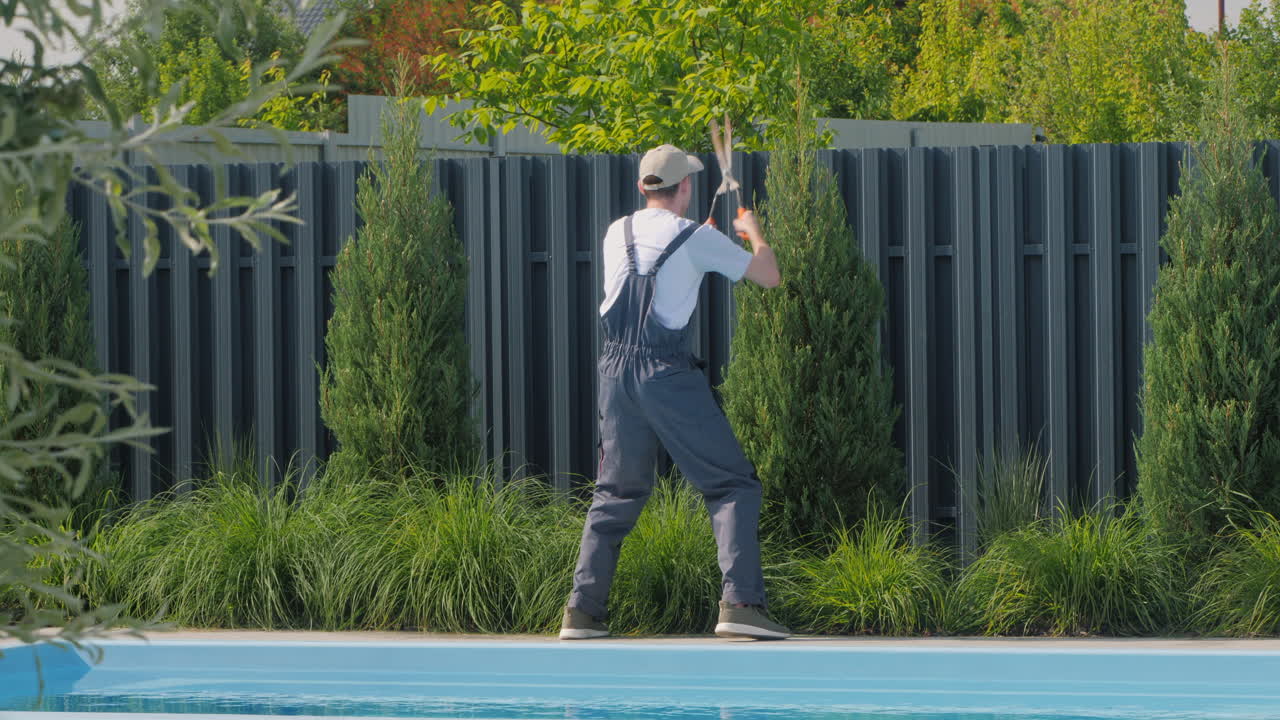 랜드스케이퍼는 수영장 에서 울타리를 잘라줍니다.