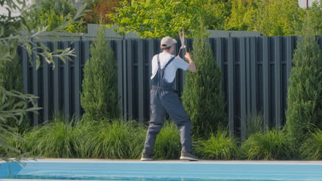 jardinero recortando setos junto a la piscina