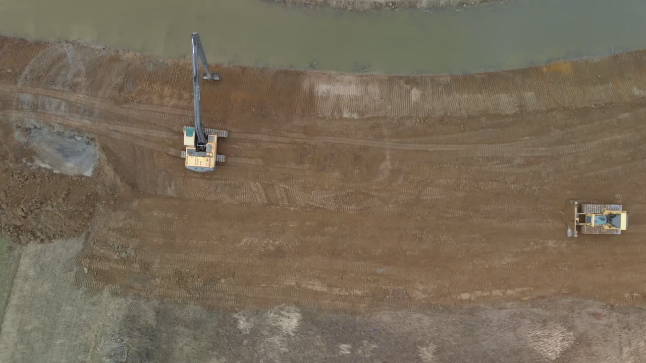 Timelapse of two excavator used to widen and deepen a river bed with sand during a rainy wet season