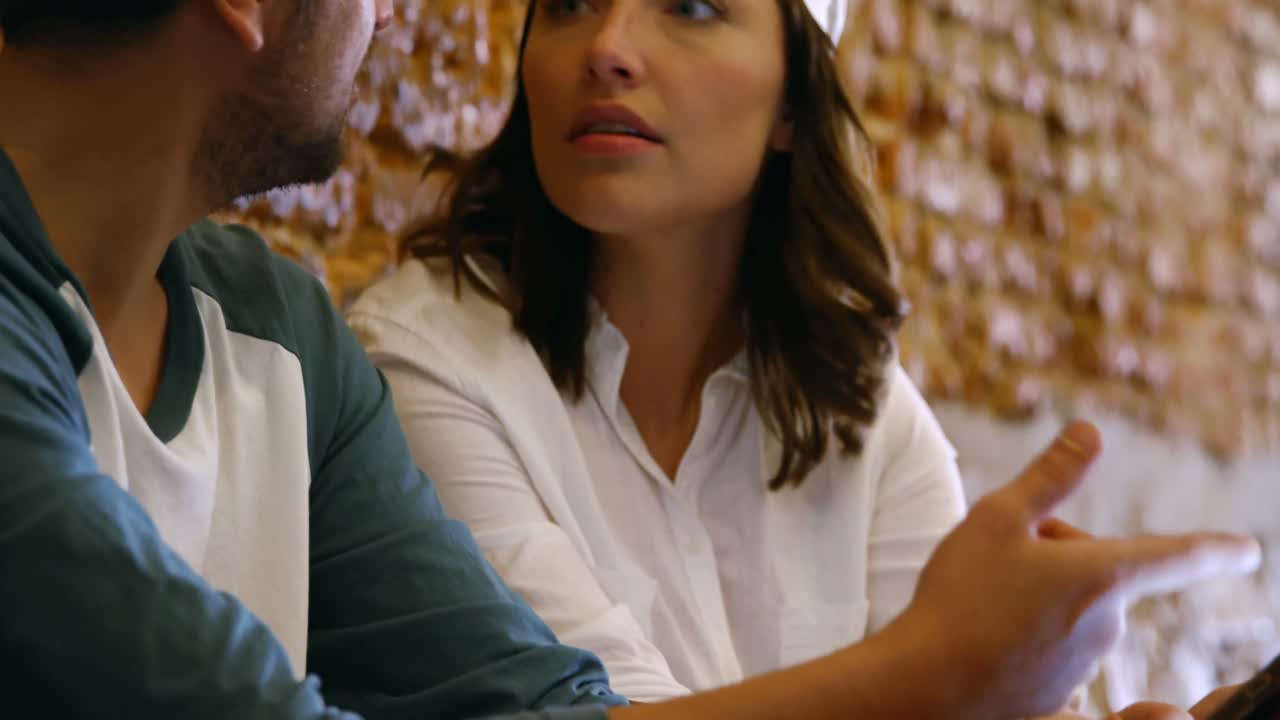 panadero masculino y femenino discutiendo sobre una tableta digital 4k