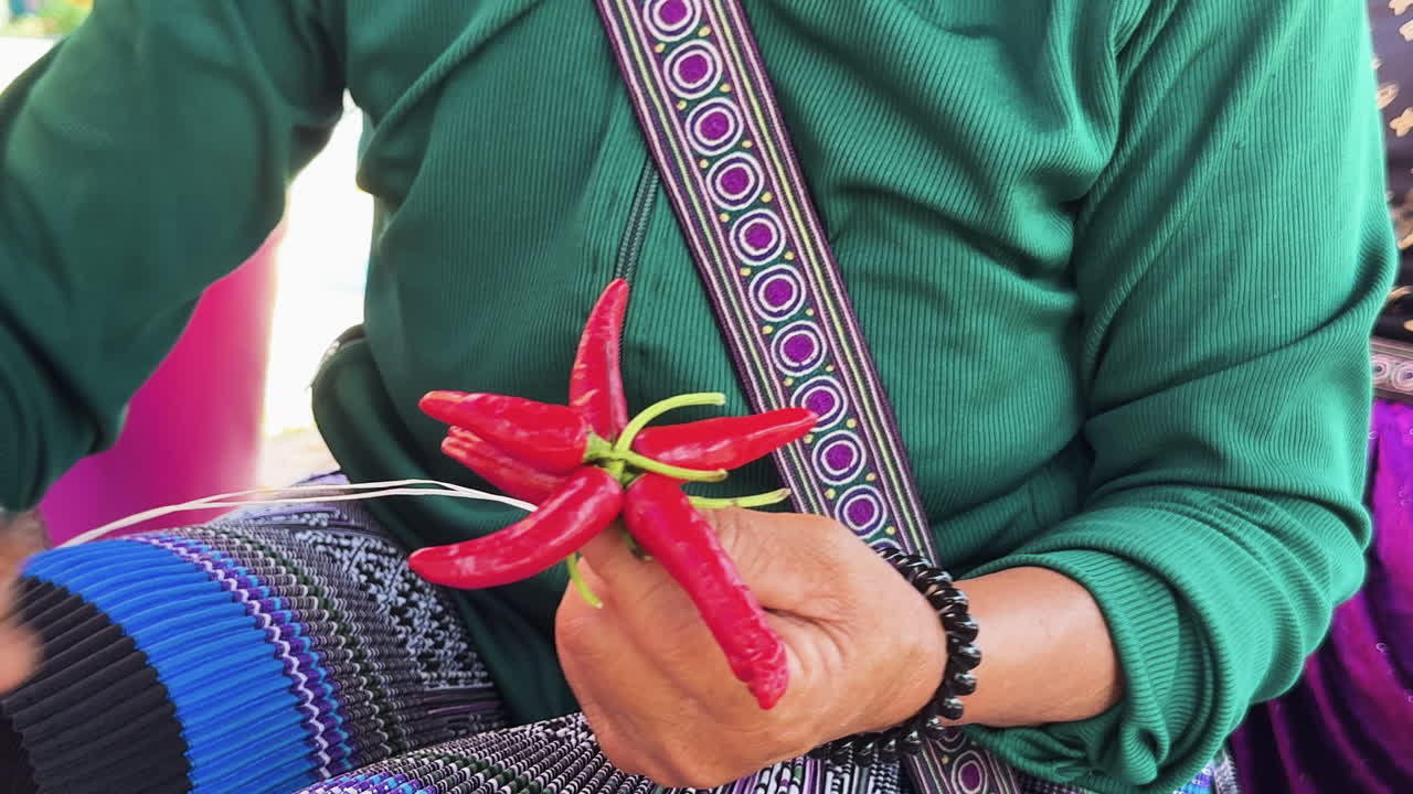 Mulher no Mercado de Domingo de Bac Ha, Vietnã, faz artesanato de pimenta com pimentas vermelhas frescas, representando a cultura étnica tradicional e o estilo de vida local.