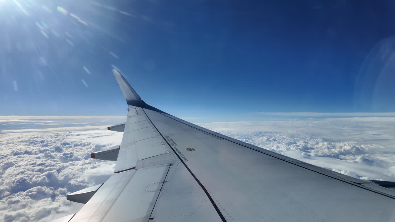Aircraft wing gliding above layered clouds viewed from the window seat