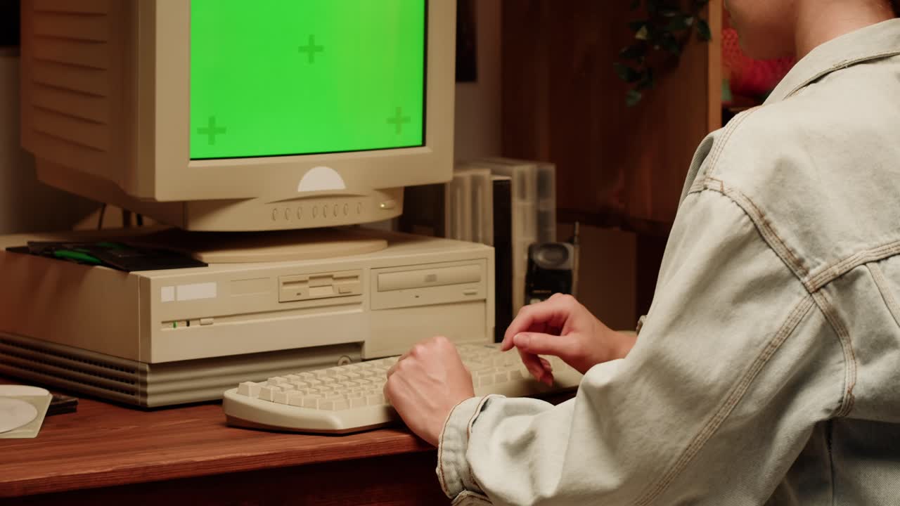 Person using a vintage computer with a green screen