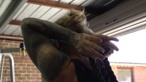 muscly man in home gym exercising overhead tricep push cable machine