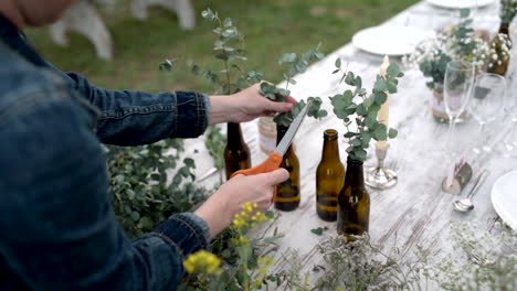 tiro de cardán de manos de floristería preparando arreglos para decorar la mesa de comida