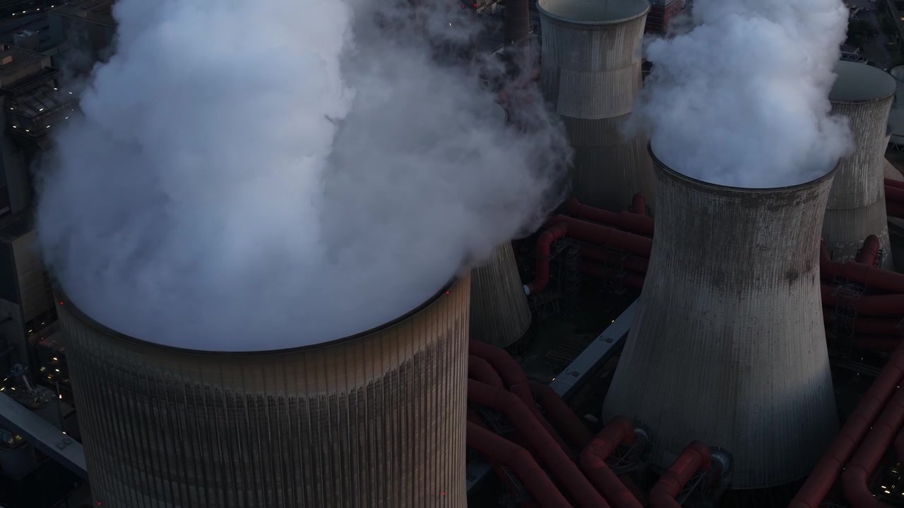 Vista aerea della centrale elettrica di Niederausem in Germania al tramonto, che mostra una massiccia centrale a combustibili fossili con torri di raffreddamento fumanti e infrastrutture energetiche industriali