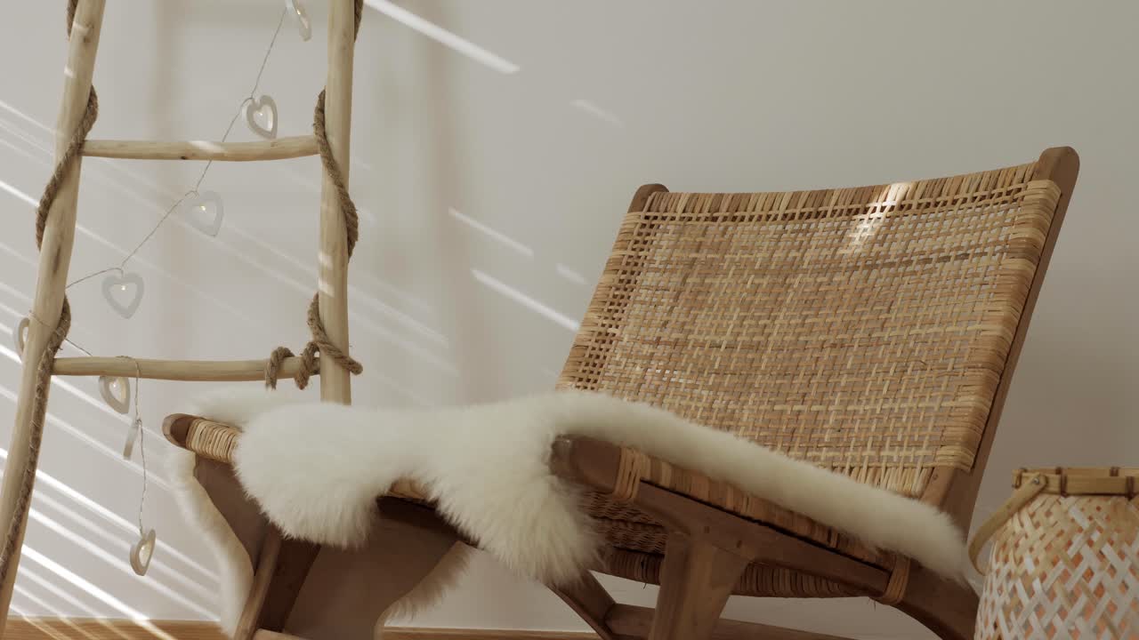 A serene shot of a wicker chair and wooden ladder, with soft sun rays gently moving on the wall and furniture