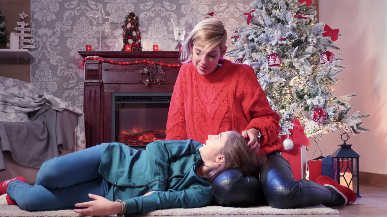 A woman and a girl in a room with a Christmas tree and fireplace