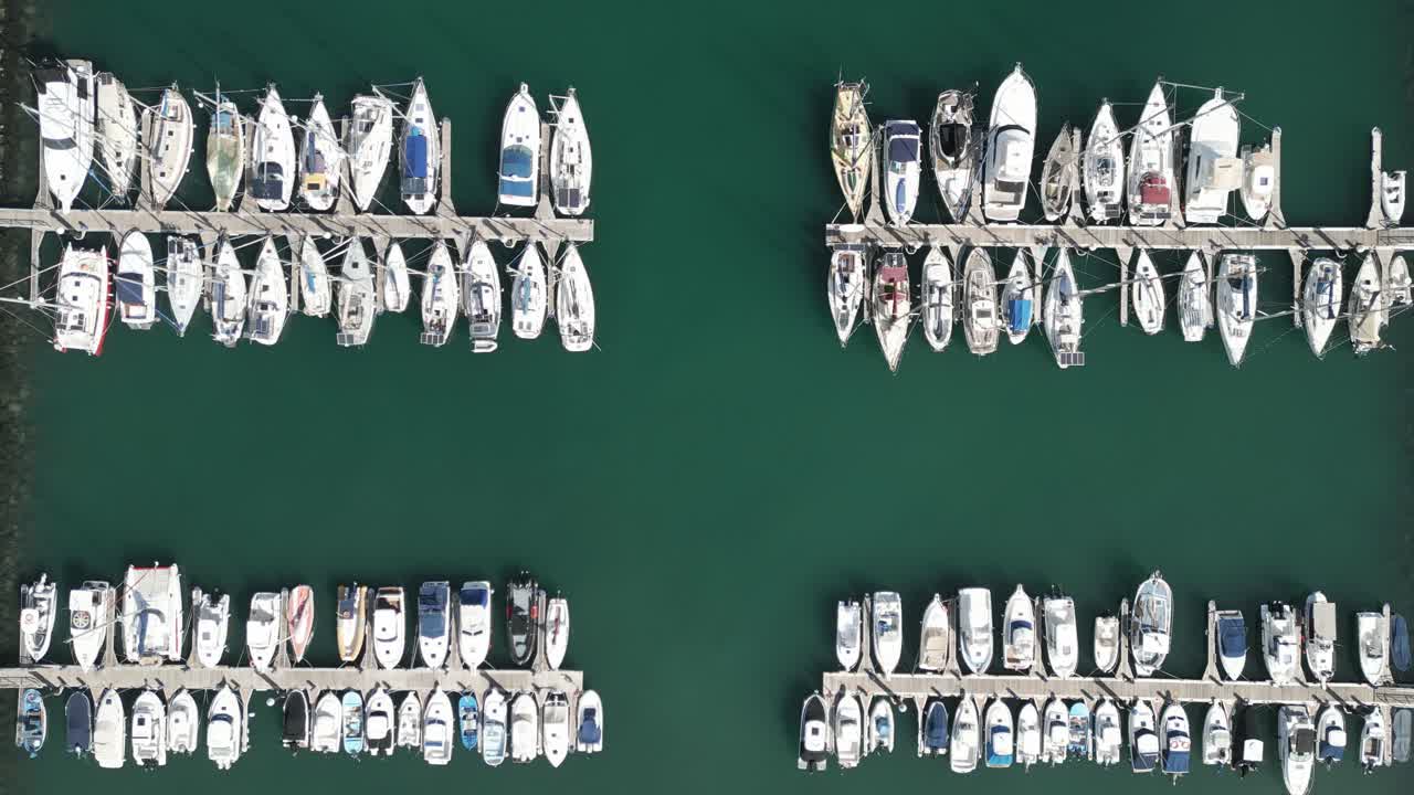 Drone bird's eye view descends on sailboats, yachts, and fishing vessels docked at new concrete pier