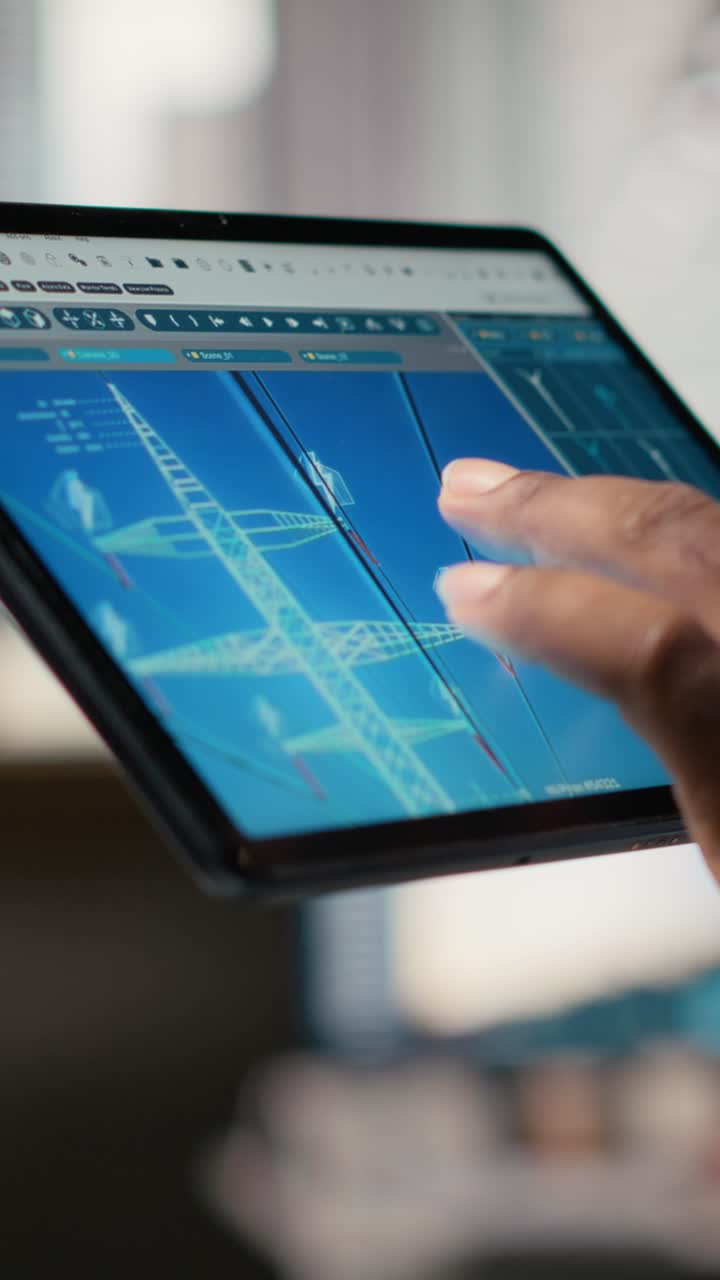 Close up of engineer using tablet to design power line towers in office