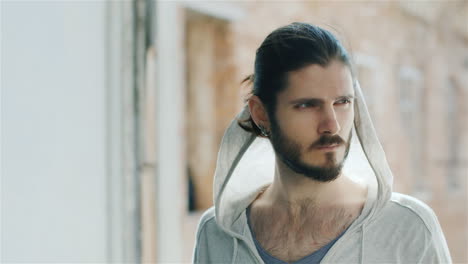 Portrait-Of-A-Little-Sad-Young-Bearded-Man-Sitting-On-The-Window-Sill-In-An-Old-House-The-Wind-Plays