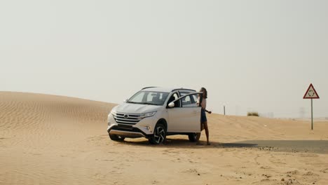 woman by a car in the desert