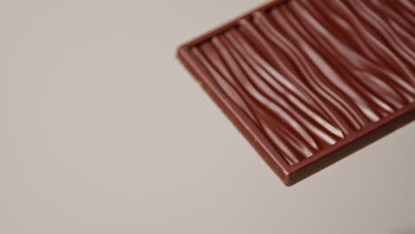 pull focus close up shot of milk chocolate bar against white background with copy space