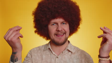 a man with a red afro wig smiles and claps his hands