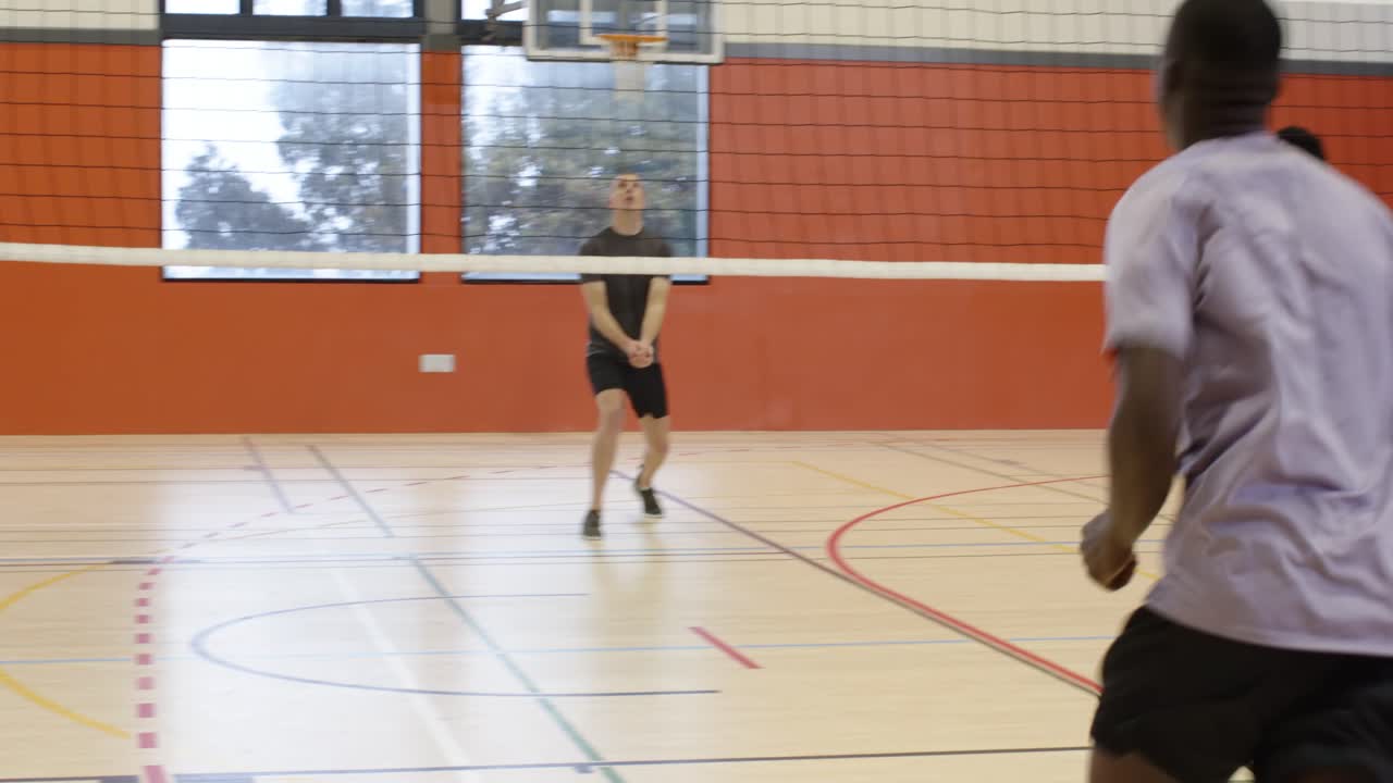 Uomini diversi, palla a terra, uomo afroamericano in maglia viola che raccoglie una palla da pallavolo in palestra, spazio per il testo