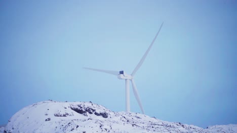 wind turbine propeller on snow mountains against blue sky
