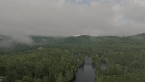 Drone-Volando-A-Través-De-Un-Hermoso-Paisaje-Neblinoso-En-La-Cima-De-La-Montaña,-Sobre-Un-Río