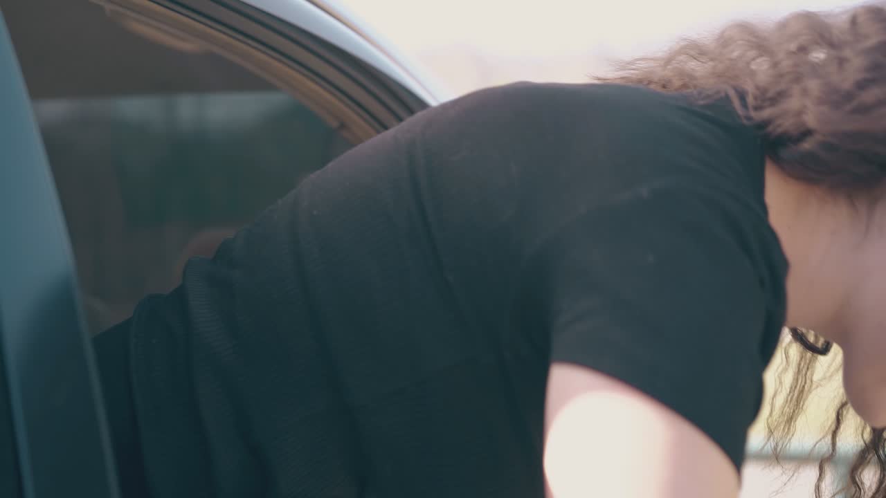 즐거운 소녀가 자동차 창문 밖으로 올라갑니다.