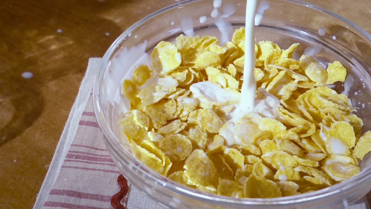 Knusprige gelbe Cornflakes in die Schale für ein köstliches Frühstück mit Milch am Morgen. Zeitlupe mit rotierender Kamerafahrt