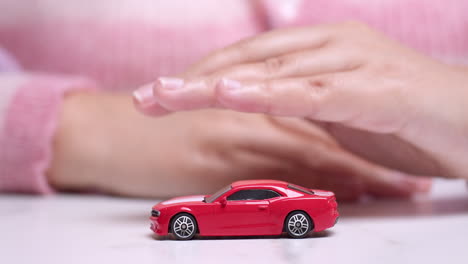 hand hovering over a red toy sportscar, manifesting the desire to own a new vehicle through a car bank loan