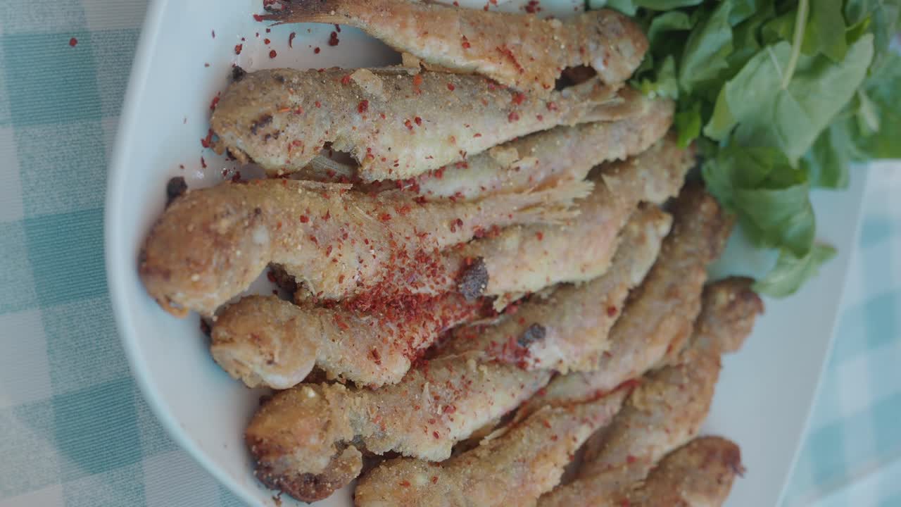 Close-up of Fried Small Fish with Greens and Red Pepper Flakes