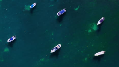 top down, close-up drone shot of boats moored in the ocean