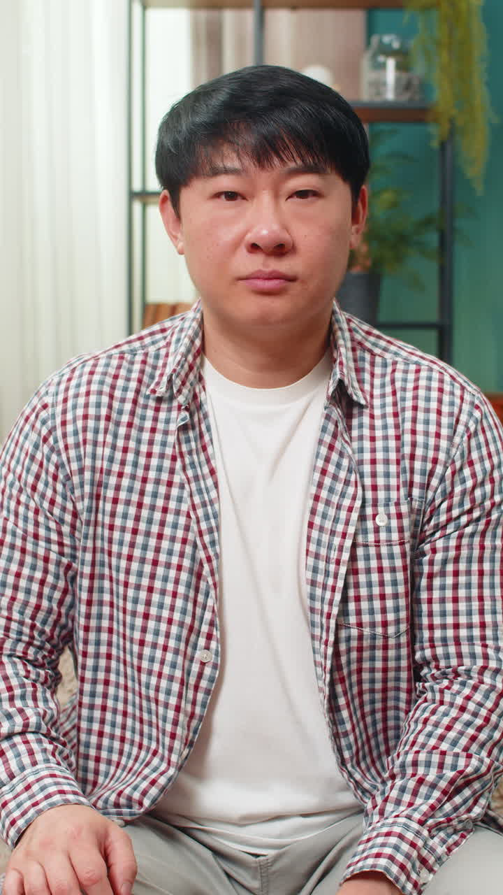 Asian man showing thumbs down unhappy dislike expression signaling strong negative disagreement