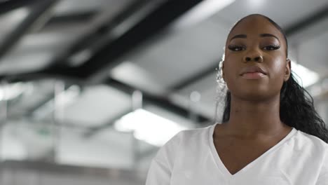 head and shoulders portrait of young woman inside office building or warehouse looking at camera