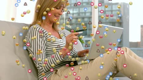animación de iconos emoji sobre mujer caucásica pagando con tarjeta de crédito con portátil.