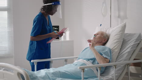 a black female surgeon is talking to an elderly male patient lying on a hospital bed. a female cardiologist infectious disease specialist is talking to a patient in the clinic