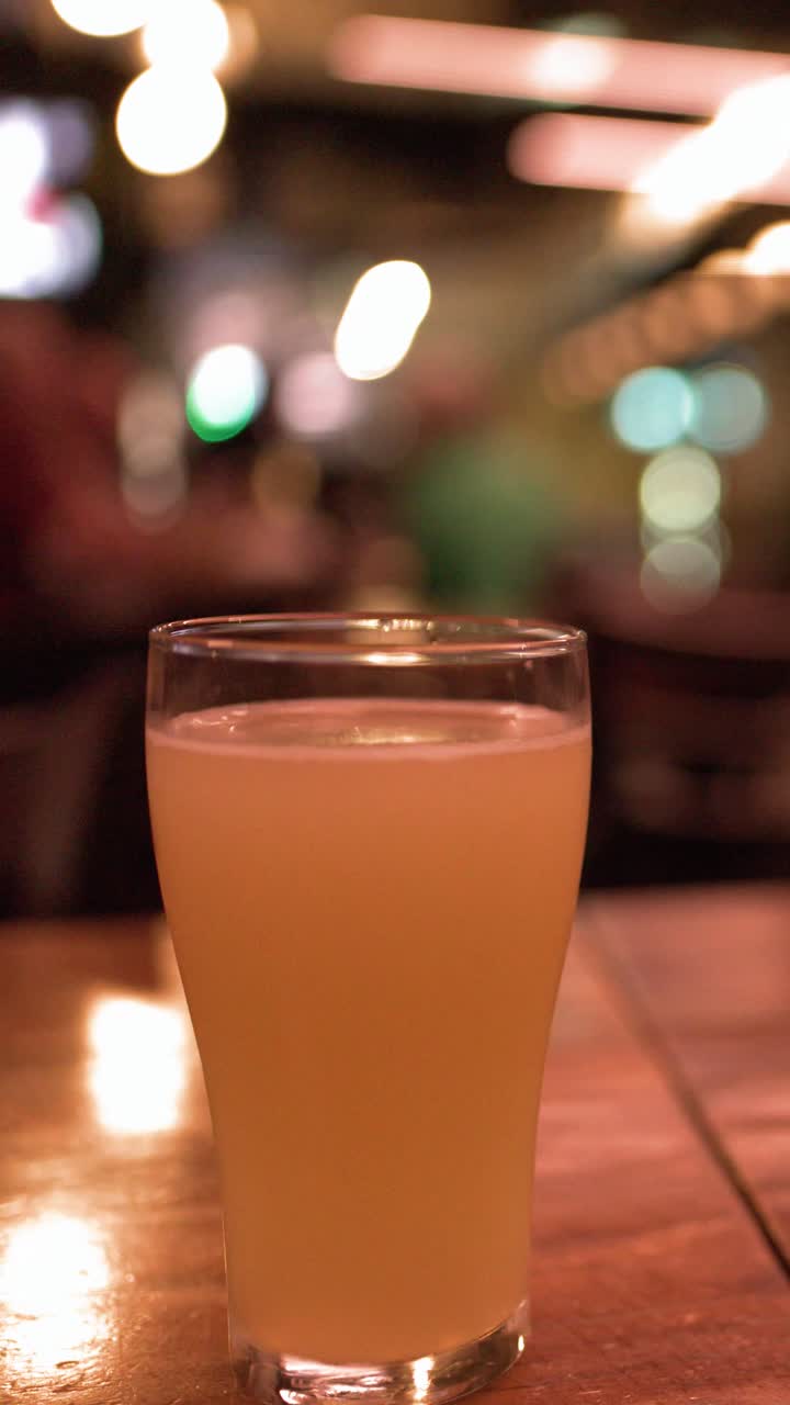 Ahşap bir pub masasında duran dolu bir bardak pale ale'in statik orta çekimi.