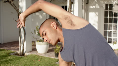 Focused-biracial-man-practicing-yoga-in-sunny-garden,-slow-motion