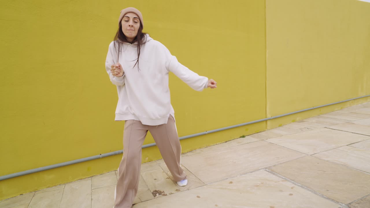 Woman dancing in front of a yellow wall