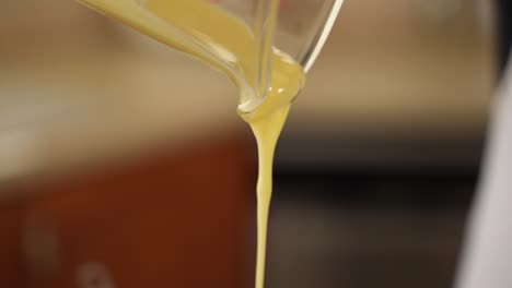 pouring liquid butter from glass measuring cup in slow motion with copy space