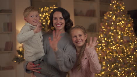 mulher, filho e filha olhando para a câmera e acenando com a mão no natal