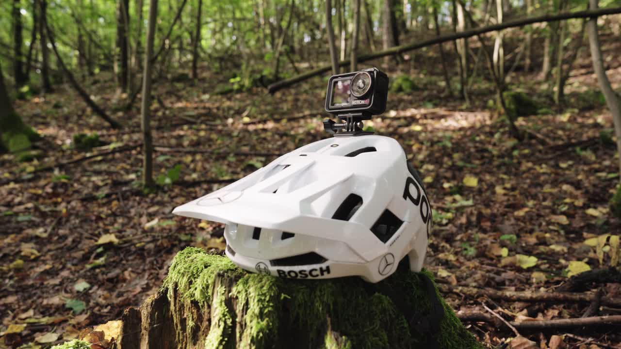 Black action camera mounted on white helmet with sponsor logos, Czechia