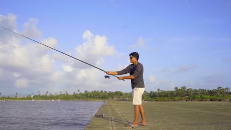 Adolescente-Edad-Niño-Pesca-Bajo-Cielo-Azul-Día-Soleado-Playa-Lenta