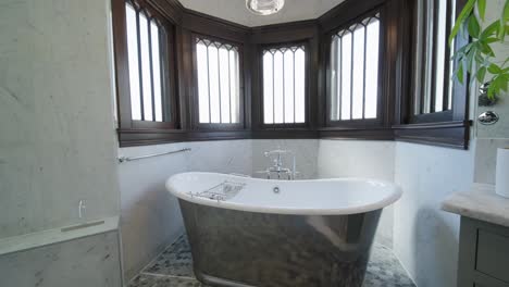 real estate push in shot of a freestanding tub surrounded by windows in the bathroom of a modern luxury home