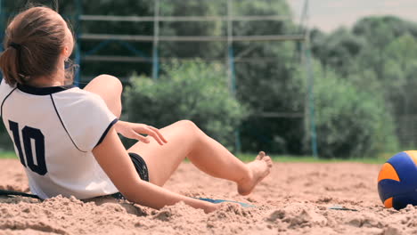 young female athlete dives into the sand and saves a point during beach volleyball match. cheerful caucasian girl jumps and crashes into the white sand during a beach volley tournament.