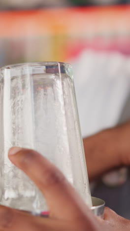 el camarero golpea el vidrio con el codo en el primer plano de la barra. el camarero negro prepara una bebida de verano con equipos de cócteles. el afroamericano disfruta del proceso de trabajo