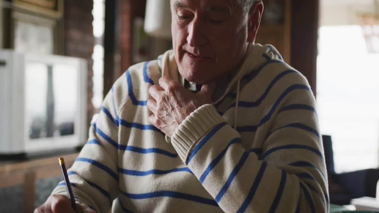 hombre mayor escribiendo en un libro en casa