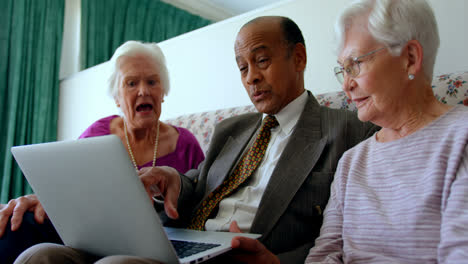 group of active mixed-race senior friends discussing over laptop in nursing home 4k