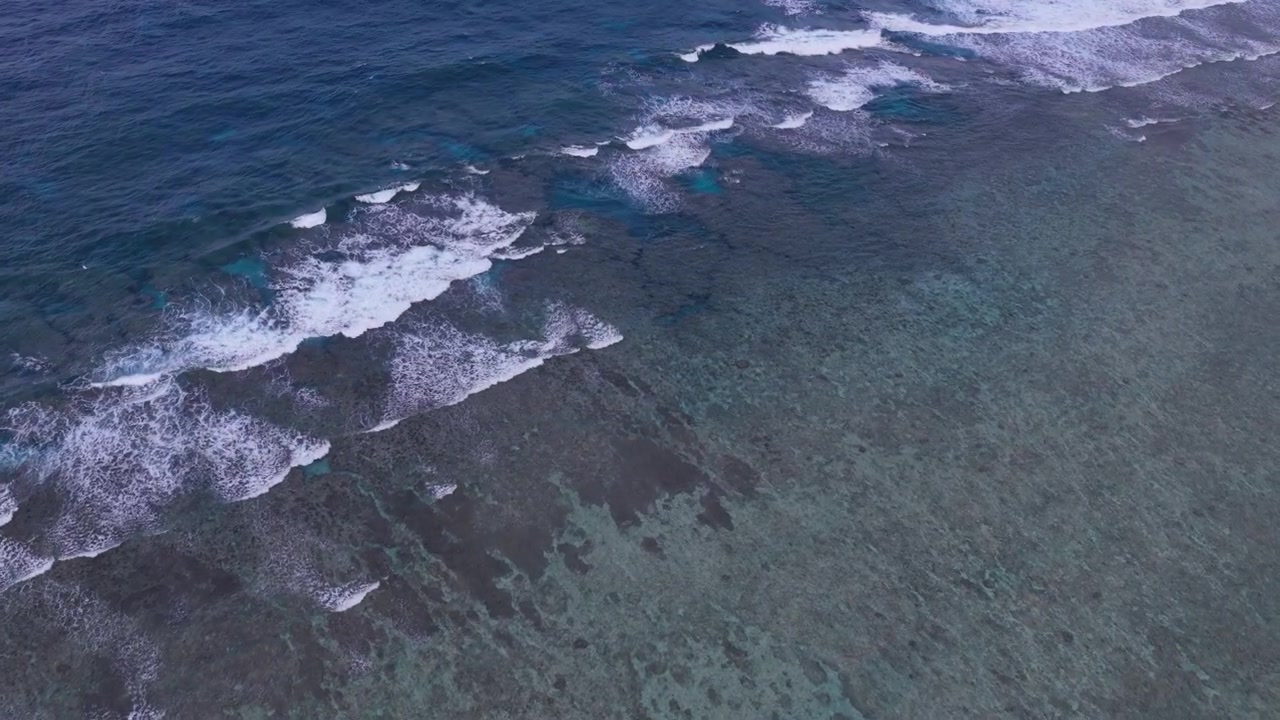 Horizontal aerial footage dollying forward above the coral reef and breaking waves near Hirano Beach and Hirakubozaki Lighthouse, Ishigaki Island, Okinawa, Japan