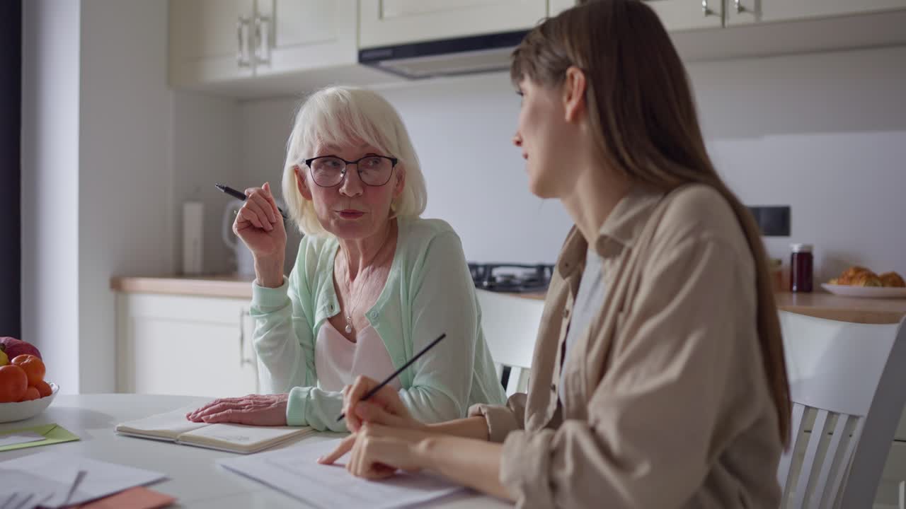 Elderly woman and young woman in kitchen having conversation