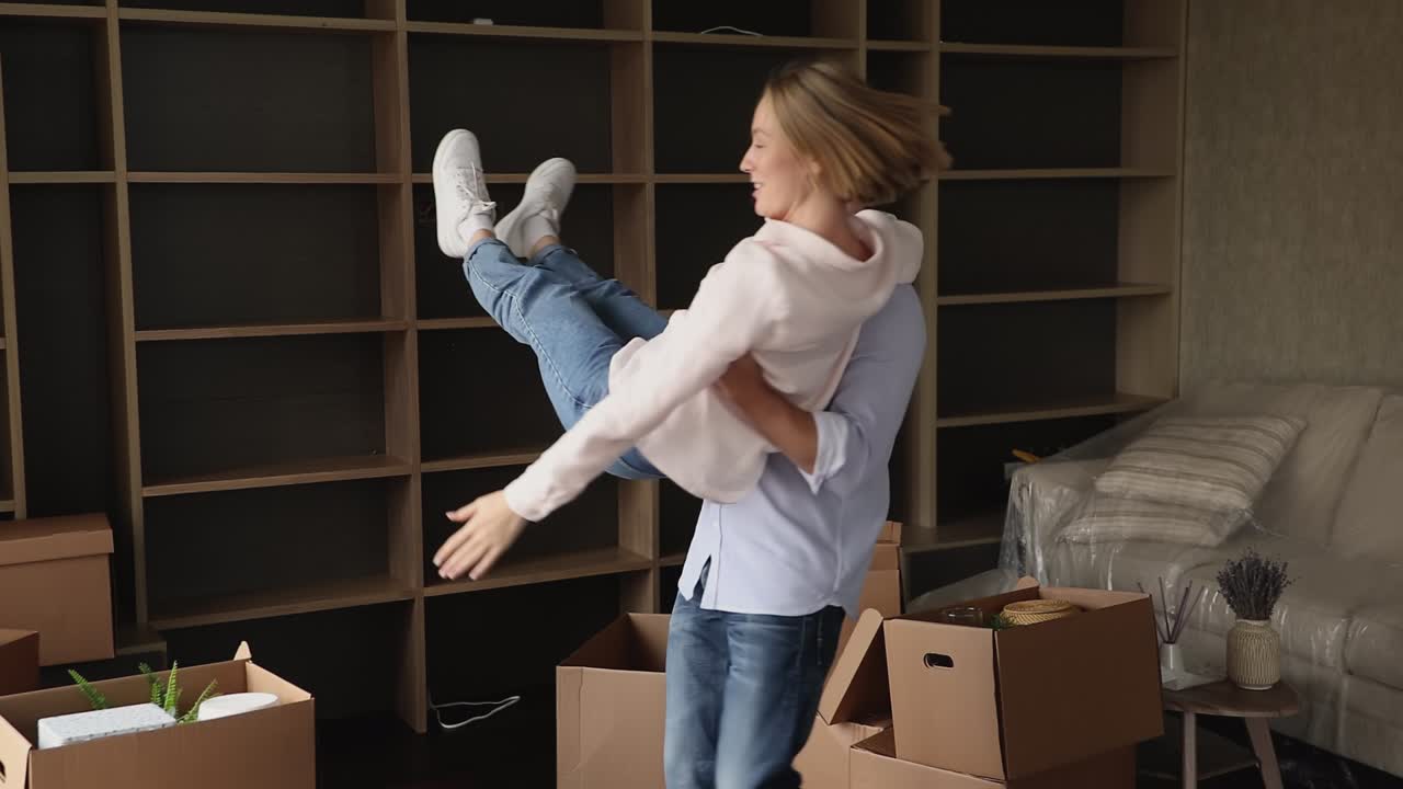 una pareja de propietarios felices bailando en la sala de estar celebrando el día de la reubicación.