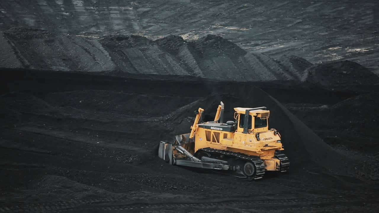 Bulldozer at coal warehouse. Tractor using for loading coal into trucks for further transport