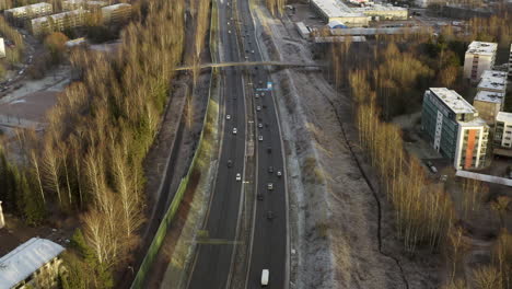 Aerial,-tilt-up,-drone-shot-of-traffic-on-the-Vihdintie-road-120,-on-a-overcast,-fall-day,-in-Pitajanmaki,-Helsinki,-Uusimaa,-Finland